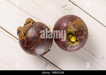 Gruppe von zwei ganze deep purple Mangosteen flatlay auf weißem Holz Stockfoto