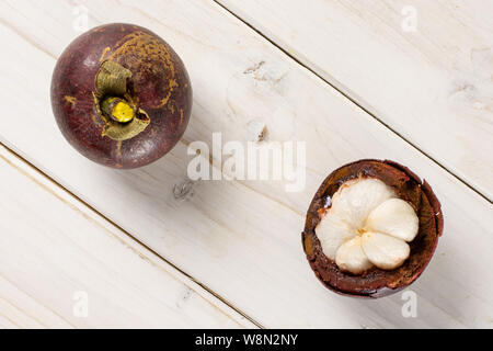 Eine ganze Hälfte von Deep Purple mangosteen flatlay auf weißem Holz Stockfoto