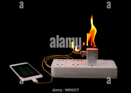 Auf Feuer Adapter Smart Phone Charger an Stecker in Steckdose auf schwarzem Hintergrund Stockfoto