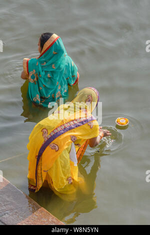 Zwei indische Hinduistische Frauen in Saris float Blume Kerzen als Opfer für die Götter (Hebe) auf dem Fluss Ganges in Varanasi, Uttar Pradesh, Indien, Asien Stockfoto