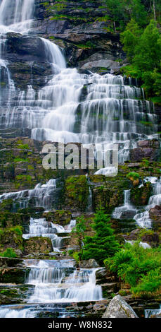 Vertikale hires Panorama von einem Wasserfall Streaming über Felsen mit Bäumen und Vegetation, Norwegen Stockfoto