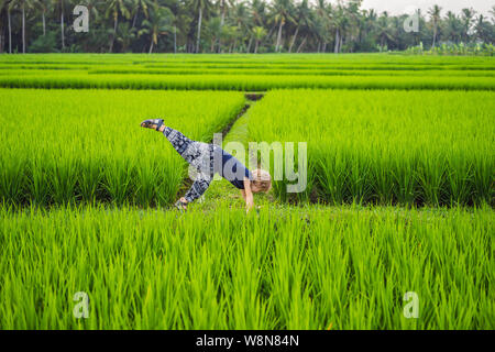 Kleiner Junge übt Yoga in einem Reisfeld, Outdoor. Gymnastische Übungen Stockfoto