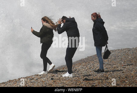 Die Leute schauen auf das Meer wie Wellen gegen Chesil Beach in Dorset, wie die Met Office in gelb Warnungen für Gewitter in Schottland und Nordirland und für starke Winde über Wales und England gesetzt hat. Stockfoto