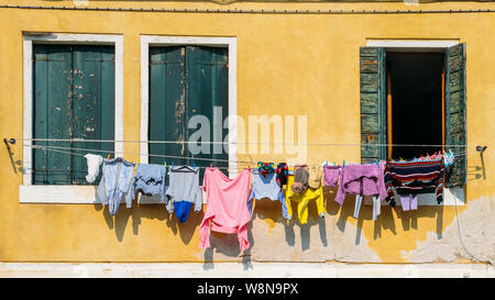 Linien der Wäsche trocknen auf Seile gespannt außerhalb bunte Fenster Fassaden in Venedig, Italien Stockfoto