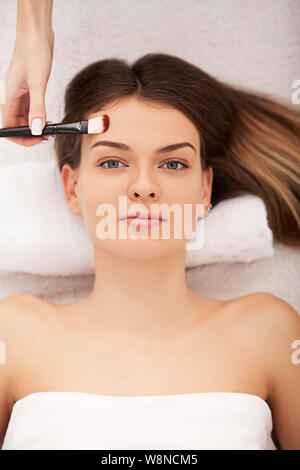 Spa. Hardware Kosmetologie. Closeup Bild der reizende junge Frau mit Creme Maske in einem Schönheitssalon. Stockfoto