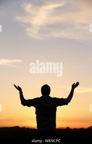 Silhouette d'un homme méditant Face à un coucher de soleil. Stockfoto