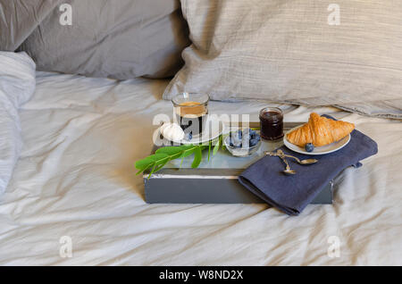 Frühstück auf grau Bettwäsche. Zwei Tasse Kaffee und Croissants mit Marmelade. Guten Morgen überraschung Konzept. Im skandinavischen Stil. Stockfoto
