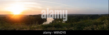 Sonnenuntergang am Horizont. Panorama-aufnahme. Ein gewundener Fluss umgeben von grünen Bäumen Stockfoto