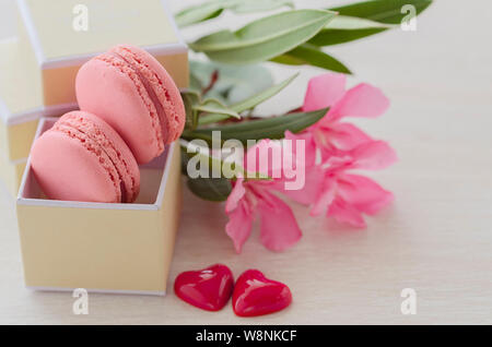 Rosa Makronen in Geschenkbox mit Blumenstrauß und zwei Herzen. Liebe und Romantische vorliegenden Konzept. Saint Valentine's Day Feier Karte. Stockfoto