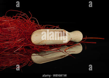 Menge ganz hellen roten Chili Threads mit Holz- Schaufel auf schwarz Glas isoliert Stockfoto