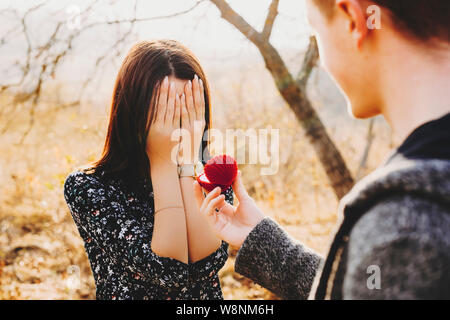 Nicht erkennbare jungen Kerl Holding offenen Ring, in der Nähe der Frau, die Ihr Gesicht mit den Händen an einem sonnigen Tag in der Natur Stockfoto