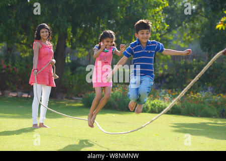 Familie spielt mit einem Seil in einem Garten Stockfoto