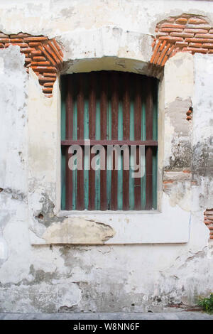 Rustikale Beton mit einem kleinen Fenster und Geländer. Peeling Beton Putz offenbart ein Backstein braun Wand Stockfoto