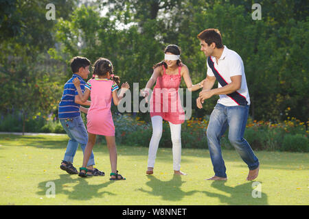 Familie spielt blinden Mann Bluff in einem Garten Stockfoto