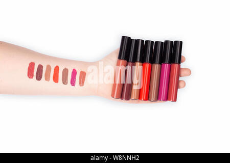 Frau Hände mit Lippenstift Probeschläge holding Lip Gloss Container, Lippenstift Muster auf weibliche Arm Stockfoto