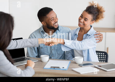 Fröhliche afro Ehegatten und finansial Ratgeber handshaking im Büro Stockfoto