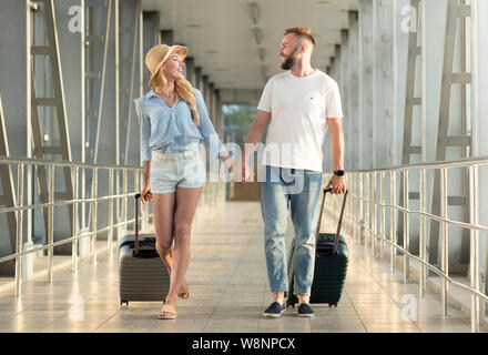 Paar Hände halten, wandern an überdachte Passage im Flughafen Stockfoto