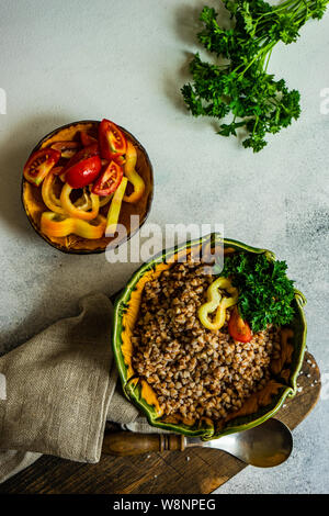 Keto Diät Konzept mit gekochten Buchweizen Saatgut und Gemüse in einem rustikalen Schüssel auf Stein mit Copyspace Stockfoto