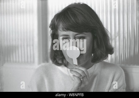 1980 s, historische, eine Dame mit einem Duft strip vor ihrer Nase, Prüfung Gerüche von einem FRAGANCE, England, UK. Stockfoto