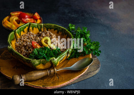 Keto Diät Konzept mit gekochten Buchweizen Saatgut und Gemüse in einem rustikalen Schüssel auf Stein mit Copyspace Stockfoto