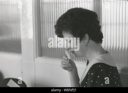 1980 s, historische, in einem Zimmer, einer Frau Duft strip vor ihrer Nase, Prüfung Duftstoffe, England, UK. Stockfoto