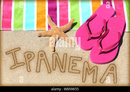 Strand von Ipanema Konzept. Ansicht von oben ot das Wort RIO auf goldenen Sand mit einem Seestern, pink Flip Flops und Handtuch konzeptionelle eines Sommer Urlaub und Reisen in Rio de Janiero, Brasilien geschrieben Stockfoto