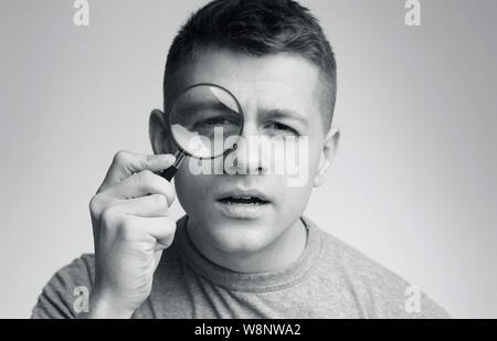 Jungen verdächtigen Mann an der Kamera über Lupe suchen Stockfoto