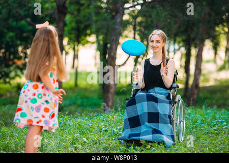 Eine junge behinderte Mädchen spielt Frisbee mit ihrer jüngeren Schwester. Interaktion von einer gesunden Person mit einer behinderten Person Stockfoto