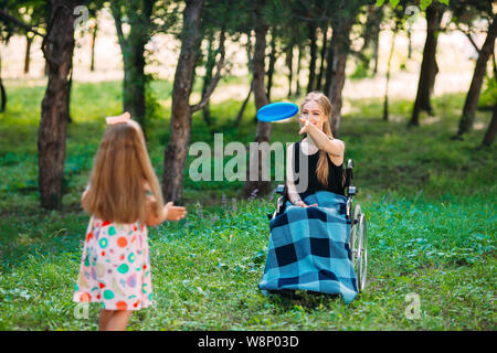 Eine junge behinderte Mädchen spielt Frisbee mit ihrer jüngeren Schwester. Interaktion von einer gesunden Person mit einer behinderten Person Stockfoto