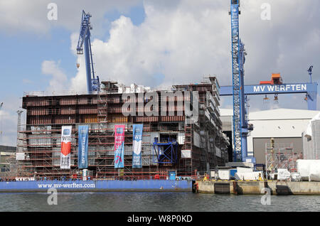 10. August 2019, Mecklenburg-Vorpommern, Rostock: Im Dock der Warnemünde Werft in MV Werften der 216 Meter langen mittleren Abschnitt der globale Klasse Kreuzfahrtschiff ist im Bau. Das Schiff ist über 342 Meter lang, 54 Meter breit und 60 Meter hoch mit 20 Etagen vom Kiel bis zu den Schornstein zu sein. Wie das Unternehmen mitteilte, ist das größte Kreuzfahrtschiff der Welt. Foto: Bernd Wüstneck/dpa-Zentralbild/dpa Stockfoto