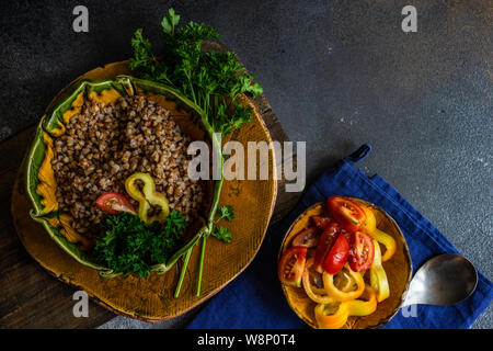 Keto Diät Konzept mit gekochten Buchweizen Saatgut und Gemüse in einem rustikalen Schüssel auf Stein mit Copyspace Stockfoto