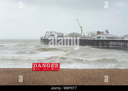 Brighton, England, UK. 10 Aug, 2019. Brighton, East Sussex. 10. August 2019. UK Wetter. Eine Band mit geringem Druck fegen über das Land bringt starke Winde und riesige Wellen zu Brighton Seafront, als Zuschauer an und dann versuchen Sie noch der Strand in dieser ungewöhnlich Negativen und Wetter zu genießen. UK Wetter Warnungen für Wind über das Land von der Met Office ausgestellt wurde, mit Böen von bis zu 60 mph an der Südküste. Credit: Francesca Moore/Alamy leben Nachrichten Stockfoto