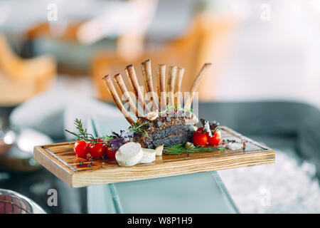 Teller Lammrücken mit Tomaten auf einer hölzernen Fach. Stockfoto
