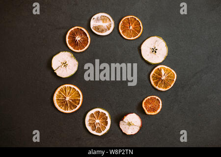 Von oben Satz von trockenen Orangen und Äpfel in Form der Kreis auf schwarzem Hintergrund Stockfoto