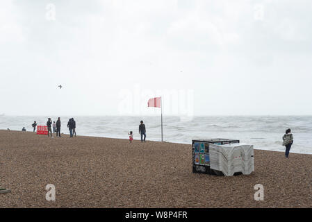 Brighton, England, UK. 10 Aug, 2019. Brighton, East Sussex. 10. August 2019. UK Wetter. Eine Band mit geringem Druck fegen über das Land bringt starke Winde und riesige Wellen zu Brighton Seafront, als Zuschauer an und dann versuchen Sie noch der Strand in dieser ungewöhnlich Negativen und Wetter zu genießen. UK Wetter Warnungen für Wind über das Land von der Met Office ausgestellt wurde, mit Böen von bis zu 60 mph an der Südküste. Credit: Francesca Moore/Alamy leben Nachrichten Stockfoto