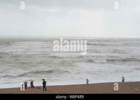 Brighton, England, UK. 10 Aug, 2019. Brighton, East Sussex. 10. August 2019. UK Wetter. Eine Band mit geringem Druck fegen über das Land bringt starke Winde und riesige Wellen zu Brighton Seafront, als Zuschauer an und dann versuchen Sie noch der Strand in dieser ungewöhnlich Negativen und Wetter zu genießen. UK Wetter Warnungen für Wind über das Land von der Met Office ausgestellt wurde, mit Böen von bis zu 60 mph an der Südküste. Credit: Francesca Moore/Alamy leben Nachrichten Stockfoto