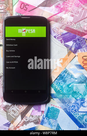 Safaricom M-Pesa fintech Mikrofinanz geld Transaction Service am Telefon mit neuen kenianischen Schilling Banknoten Hintergrund Stockfoto