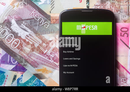 Safaricom M-Pesa fintech Mikrofinanz geld Transaction Service am Telefon mit neuen kenianischen Schilling Banknoten Hintergrund Stockfoto