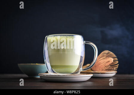 Matcha grüner Tee Latte mit Matcha Pulver und bambusbesen auf schwarzem Hintergrund closeup Stockfoto