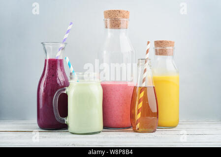 Orange, Grün und Rot gefärbte Smoothies und Saft in ein Glas Gläser auf einem blauen Hintergrund. Stockfoto