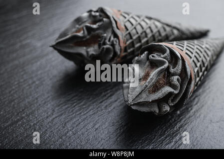 Schwarzes Eis in Kegel auf schwarzem Schiefer Hintergrund closeup Stockfoto