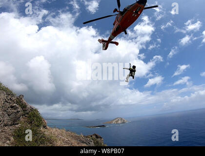 Eine Air Station Herrenfriseure Punkt MH-65 Dolphin Hubschrauberbesatzung führt aus Training die Klippen in der Nähe von Makapu'u Leuchtturm, Hawaii, Aug 7, 2019. Die Klippen bieten eine herausfordernde und realistische Umgebung für die Besatzungen für mögliche Vorfälle in der Zukunft vorzubereiten. (U.S. Coast Guard Petty Officer 1st Class Robin Pietschmann/freigegeben) Stockfoto