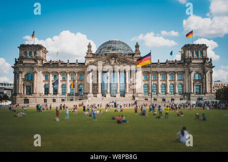 Berlin, Deutschland - August 2019: Viele Menschen auf der Wiese vor dem Reichstagsgebäude (Deutscher Bundestag), ein Wahrzeichen an einem sonnigen Sommertag Stockfoto