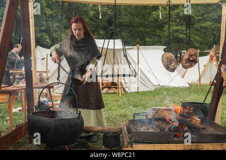 Bouillon, Belgien. 10 Aug, 2019. Eine Frau im mittelalterlichen Stil Kleidung bereitet Essen während der jährlichen Mittelalter Festival in der Stadt Bouillon in Belgien, 10.08.2019. Die jährlichen Mittelalter Festival in Bouillon am Samstag begann, mit zeigt, kämpft und das Handwerk von mittelalterlichen Stil Touristen, die bis in das Mittelalter zurück. Credit: Zheng Huansong/Xinhua/Alamy leben Nachrichten Stockfoto