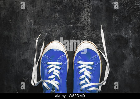 Blau - blaugrün - Grün - türkis Sneaker mit Ungebundener Schnürsenkel auf einem dunklen konkreten Hintergrund. Kopieren Sie Platz. Ansicht von oben Stockfoto