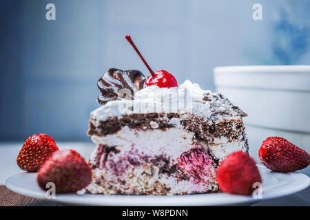 Stück Torte mit Kirschen und Erdbeeren, die auf weiße Platte. Stockfoto