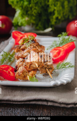 Saftiges Fleisch - hähnchenspieße auf Holzspieße auf einem weißen Teller auf einem dunklen Hintergrund. Stockfoto