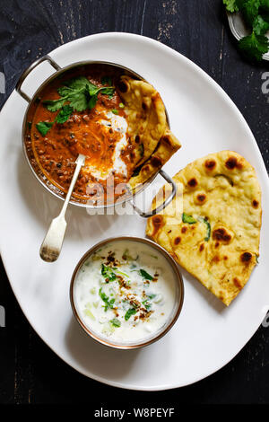 Indisches essen Curry mit schwarzen Linsen dal, Naan Brot und raita Stockfoto