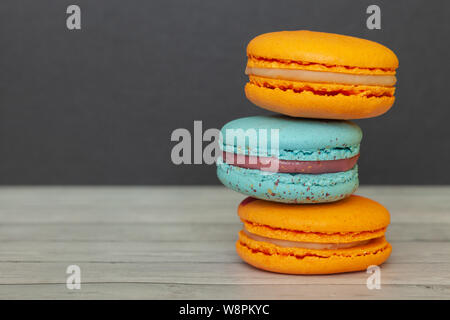 Orange und Blau Makronen auf einem dunklen Hintergrund, Französisch cookies als Wohltat für den Urlaub Stockfoto