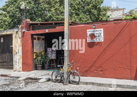 Äußere Aufnahme des Restaurant La Casa de las Sopas, mit einer gepflasterten Straße und ein Fahrrad stützte sich auf einen Post, in Antigua, Guatemala Stockfoto